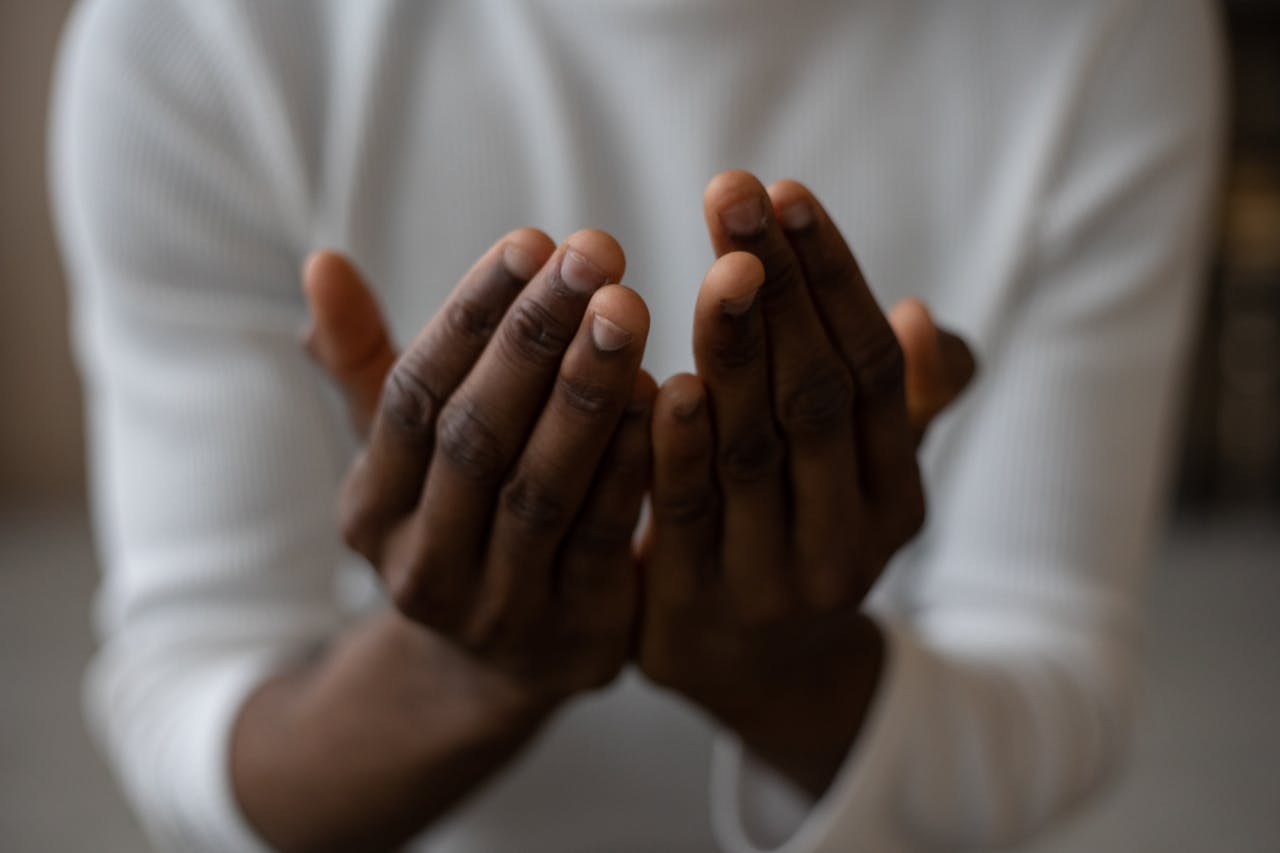 A close-up shot of an African American man's hands in a prayer gesture, conveying spirituality and tranquility.